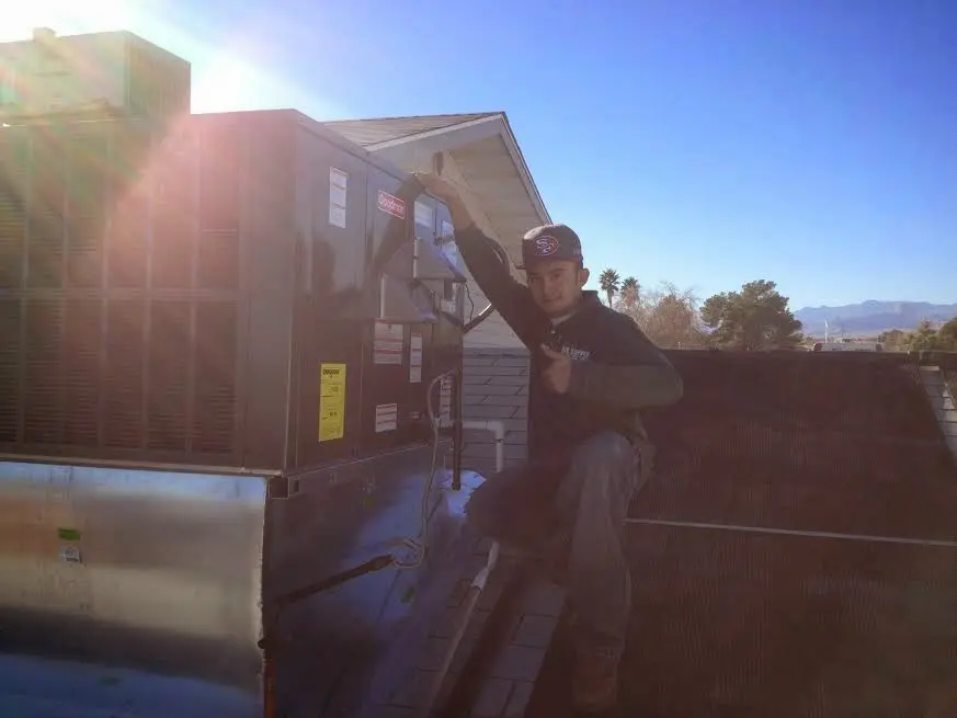 HVAC technician performing HVAC Inspection on a rooftop unit in Milton